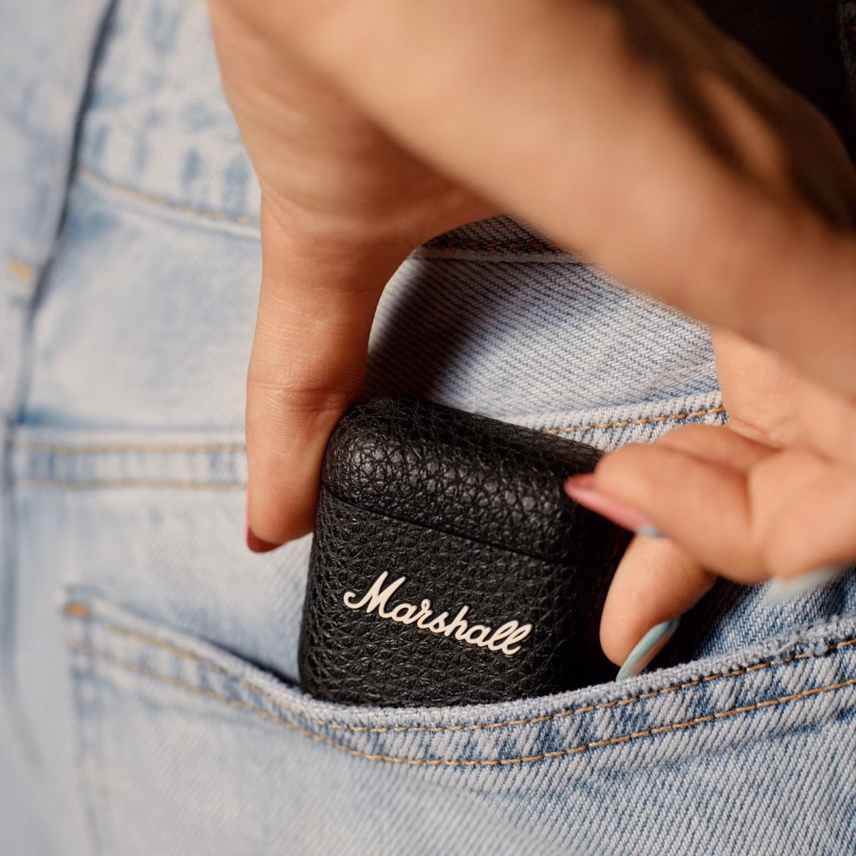 Дівчина дістає зарядний кейс Marshall Minor IV Black з кишені джинсів